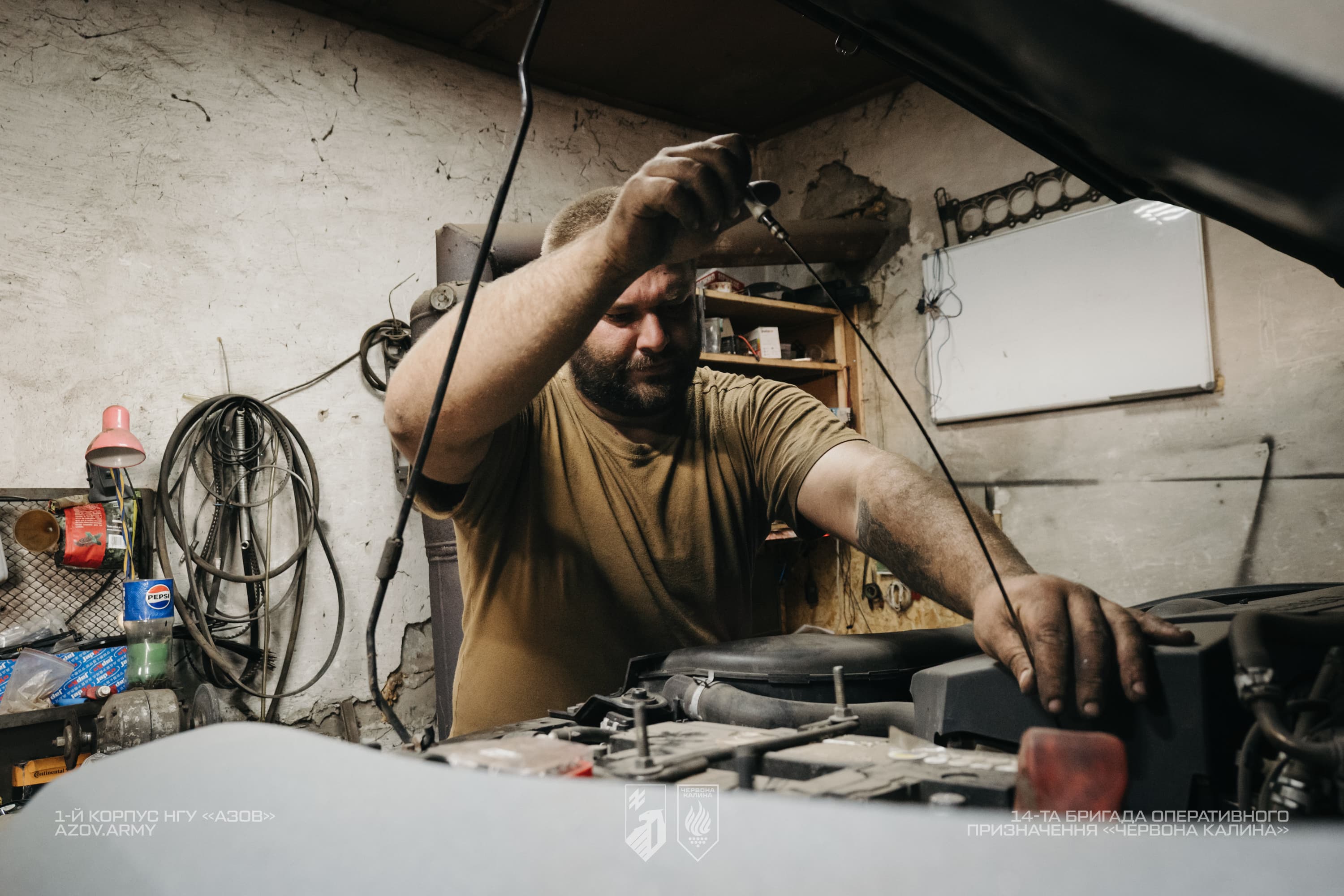 Механік 14-ї бригади «Червона Калина» проводить технічне обслуговування автомобіля під відкритим капотом.