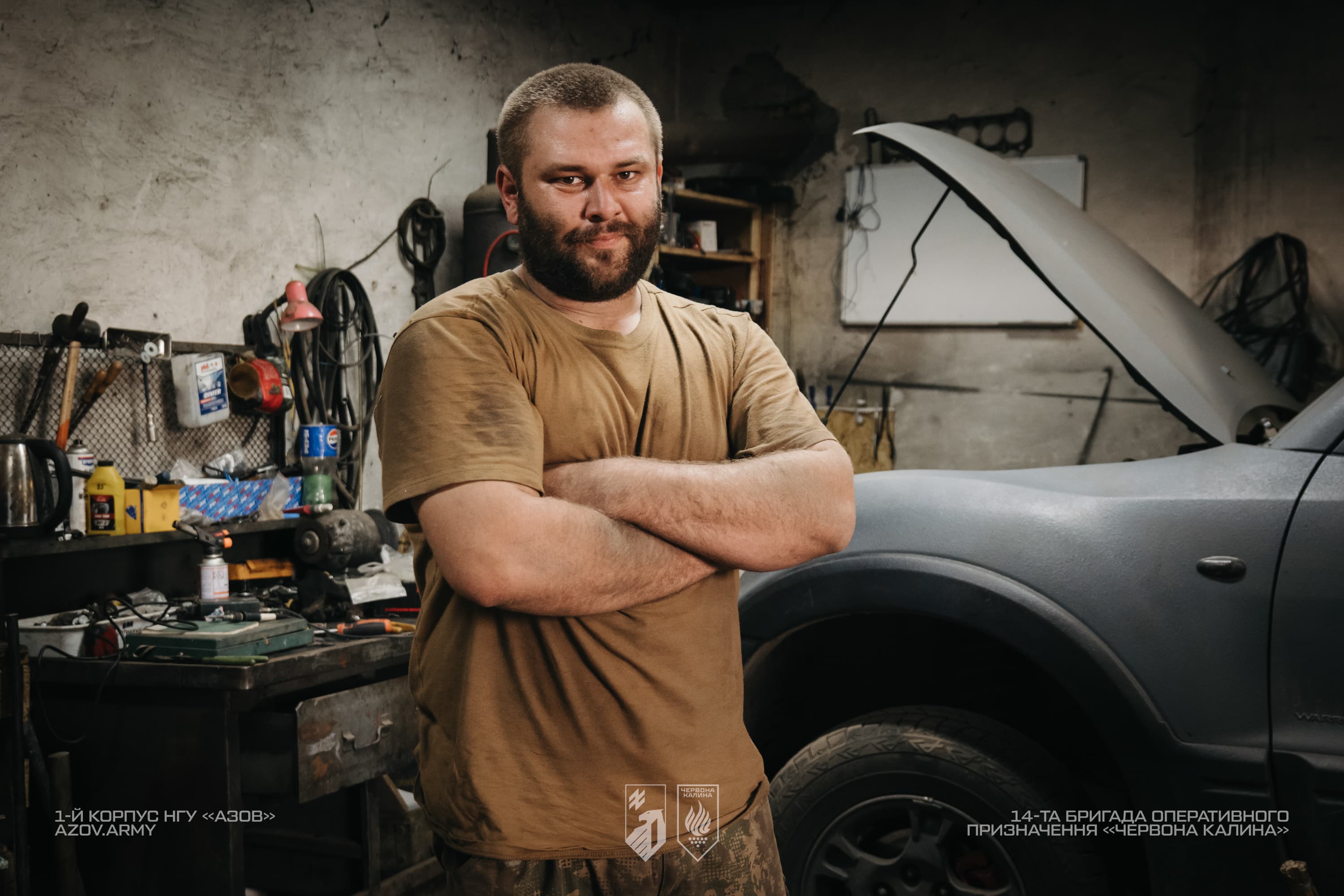 Портрет механіка «Скіфа» з 14-ї бригади «Червона Калина» на тлі військового пікапа в ремонтній майстерні.